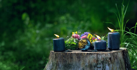 amulet, candles and flowers on stump, abstract natural forest background. Wiccan, Slavic magic practice for Litha, Midsummer holiday. Witchcraft, esoteric spiritual ritual, divination