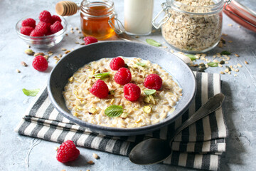 Healthy breakfast. Oatmeal porridge with raspberries, sunflower seeds, pistachio and honey. Top view. - obrazy, fototapety, plakaty