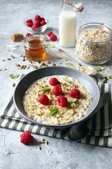 Healthy breakfast. Oatmeal porridge with raspberries, sunflower seeds, pistachio and honey. Top view.