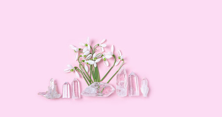 Quartz gemstones and spring snowdrops flowers on abstract pink background. minerals for esoteric spiritual practice, soul relax, meditation, witchcraft. Magic crystal ritual for life balance, harmony.