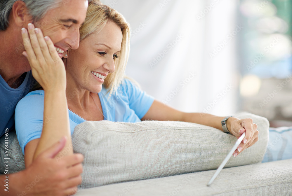 Poster staying in touch couldnt get any easier. a smiling couple sitting at home using a digital tablet.