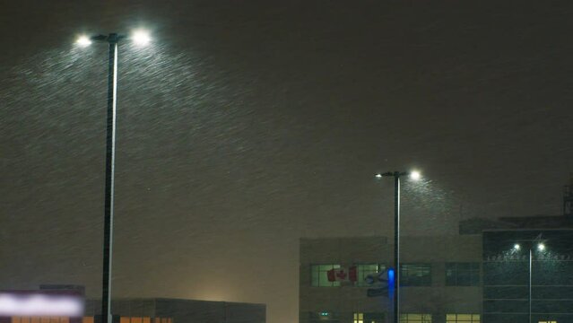 Row of high night lanterns with heavy storm snow at night. Curtain weather conditions in winter Canada, Halifax. Strong wind with sleet against the background of glowing lanterns. 