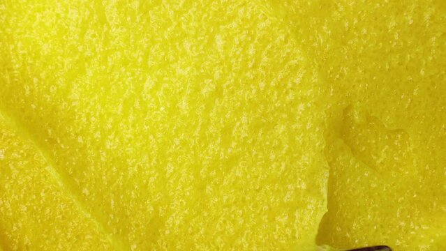 Top view of bright yellow lemon exfoliating sugar body scrub texture smears close up