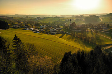 Fototapeta premium Wonderful aerial view of the evening atmosphere over Zell am Pettenfirst, Austria, where the old church and other buildings cast very long shadows