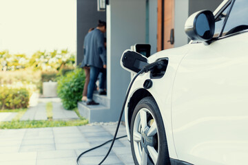 Focus closeup electric vehicle recharging battery from home electric charging station with blurred...