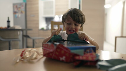 Child opening present. One small boy unwrapping gift