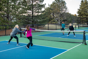 Four Female Pickleball Players Volley near the Net