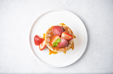 Sweet souffle pancakes decorated with fresh strawberries in a plate