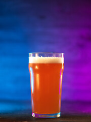 Craft beer glass on a dark background with neon colored backlight - obrazy, fototapety, plakaty