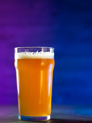 Craft beer glass on a dark background with neon colored backlight