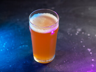 Craft beer glass on a dark background with neon colored backlight