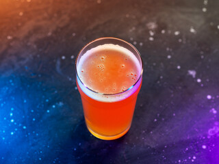 Craft beer glass on a dark background with neon colored backlight