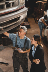 Vehicle automotive service guy worker doing check or mend car wheel, Asian mechanic repairman look under car condition to work in inspection workshop or maintenance to repair car engine in garage