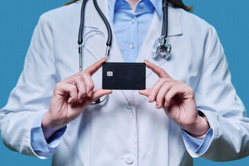 Close-up credit card in hands of doctor, on blue background