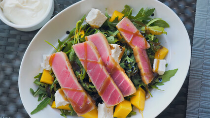 Raw Tuna sashimi salad with a mix of fresh fruit, cheese, and arugula