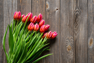 Bouquet of fresh pink tulips in a string bag on a wooden background, top view, concept of mother's day, women's day, spring background with a bouquet of flowers, rustic style.