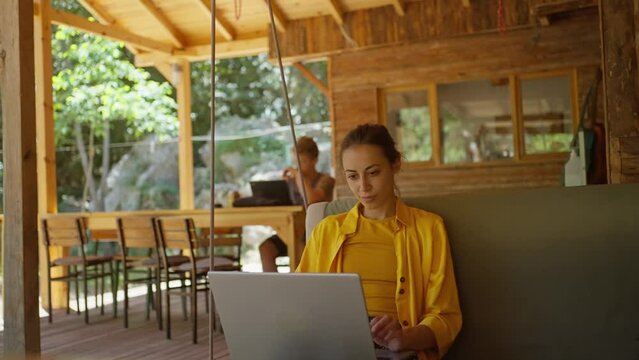 Pensive woman freelancer working on laptop computer at terrace in camping during travel. Concept remote work, freelance