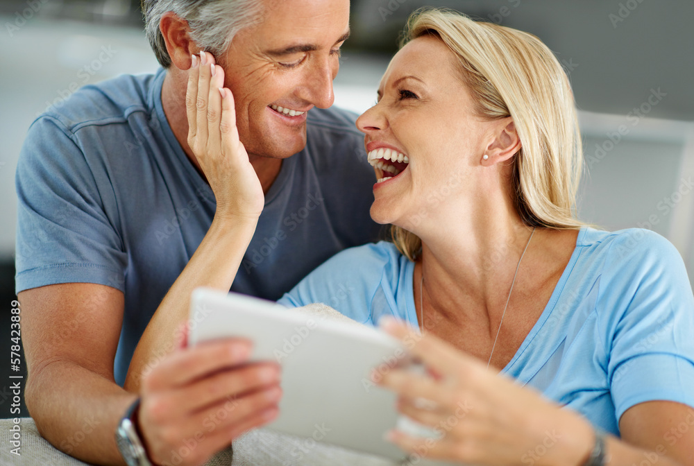 Poster who doesnt like a good meme. a laughing couple sitting at home using a digital tablet.