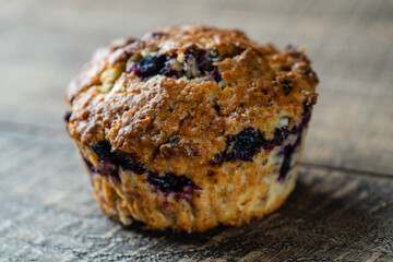 Delicious muffin with blueberries on a wooden table, closeup. Sweet pastries on the board. Fresh cupcake for breakfast