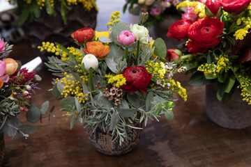 Beautiful flower arrangement of persian buttercups, wax flower, cut mimosa, eucalyptus branches in...