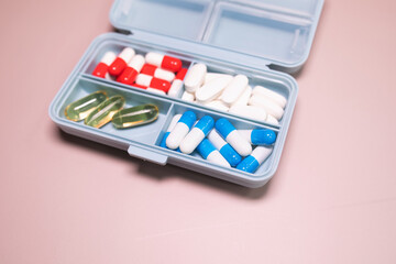 Pill box daily take a medicine, with colorful of pills, tablets, and capsules on beige bacground. Medicine, health concept.