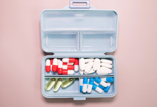 Pill box daily take a medicine, with colorful of pills, tablets, and capsules on beige bacground. Medicine, health concept.