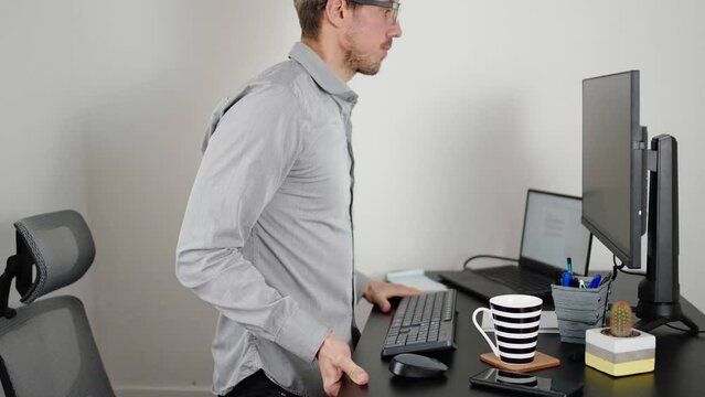 Business man working at home while adjusting the height of his standing desk