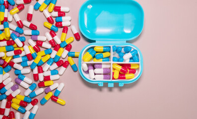Pill box daily take a medicine, with colorful of pills, tablets, and capsules on beige bacground. Medicine, health concept.