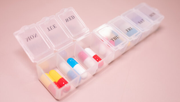 Pill box daily take a medicine, with colorful of pills, tablets, and capsules on beige bacground. Medicine, health concept.