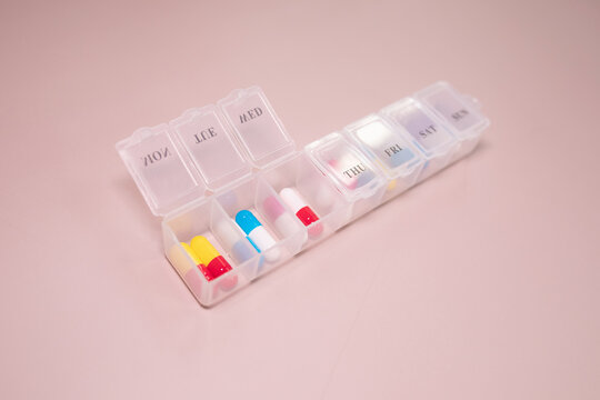 Pill box daily take a medicine, with colorful of pills, tablets, and capsules on beige bacground. Medicine, health concept.