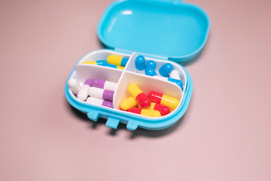 Pill box daily take a medicine, with colorful of pills, tablets, and capsules on beige bacground. Medicine, health concept.