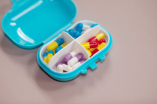 Pill box daily take a medicine, with colorful of pills, tablets, and capsules on beige bacground. Medicine, health concept.