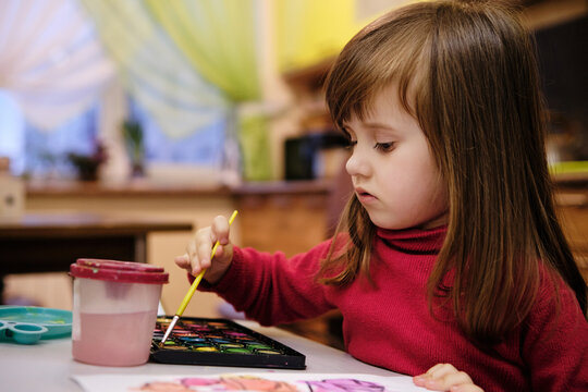 Little girl painting with water colors.