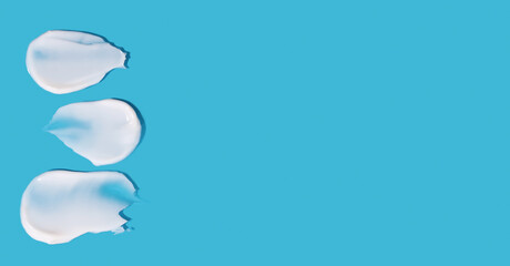 Cosmetic smears of cream texture on a blue background. banner Copy space.