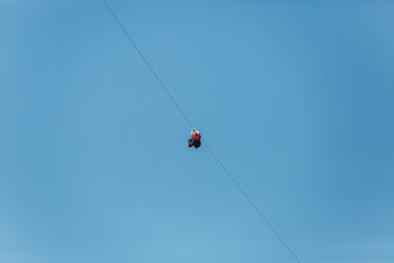 Man having fun on a zip line at summer against blue sky