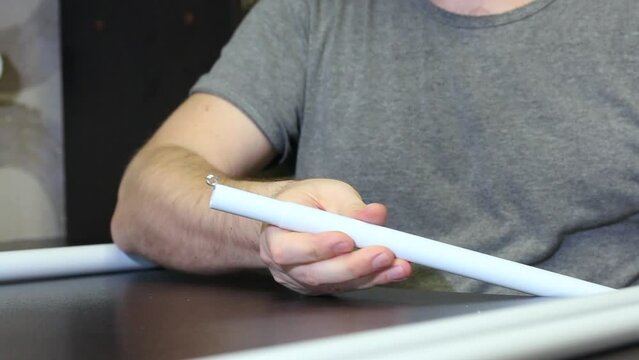 A man demonstrates parts for a garden awning. Connects tubes and adapters. Shot close-up