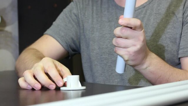 A man demonstrates parts for a garden awning. Connects tubes and adapters. Shot close-up.