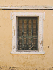 window with closed shutter on a facade of an abandoned house