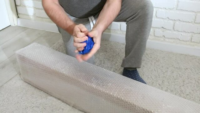 A man unpacks a package. Rip off the packing tape. Garden tent in bubble wrap.