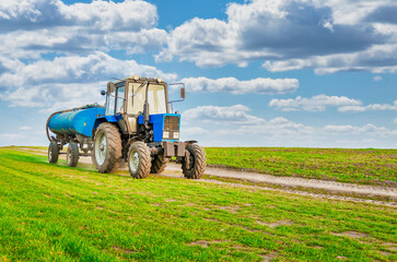 An agricultural tractor drives along a field road. Spring Field