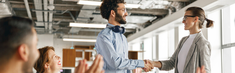 Smiling female boss leader shaking hand of new team member recruiting him for job on staff briefin