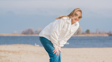 Fototapeta na wymiar Woman in white jacket, sunglasses and blue jeans at the beach, new collection, fashionable trend