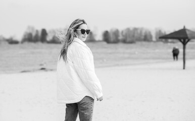 Woman in white jacket, sunglasses and blue jeans at the beach, new collection, fashionable trend