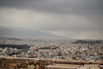 View on Athens streets from Pantheon on winter during cloudy cold day with snow on the mountain in background