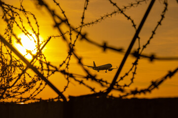View through barbed wire on a flying plane at sunset. 