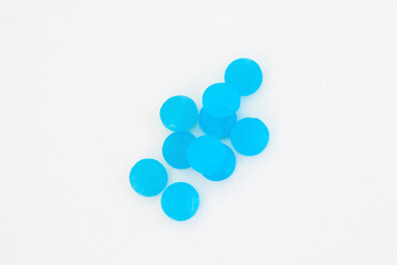 blue lozenges on orange surface,stethoscope on rock heap stack of plastic blister packs one over another,surgical gloves.hand remove from blister one candy.ear tips tubes in shadow sun.medical tablets