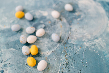 Pastel spring background with blue, yellow and white painted eggs on a beautiful blue and turquoise canvas. Mock up. Space for text