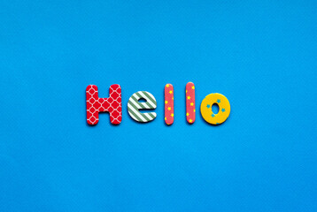 word Hello from bright colored paper letters on blue paper background