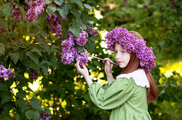 girl with long red hair draws in a lilac garden