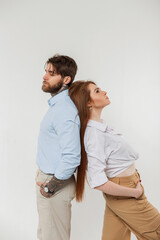 Fashionable handsome couple handsome hipster man and beautiful redheaded woman in stylish casual clothes with shirt standing back to back in the studio